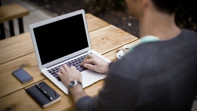 ノートパソコンで記事をまとめる男性